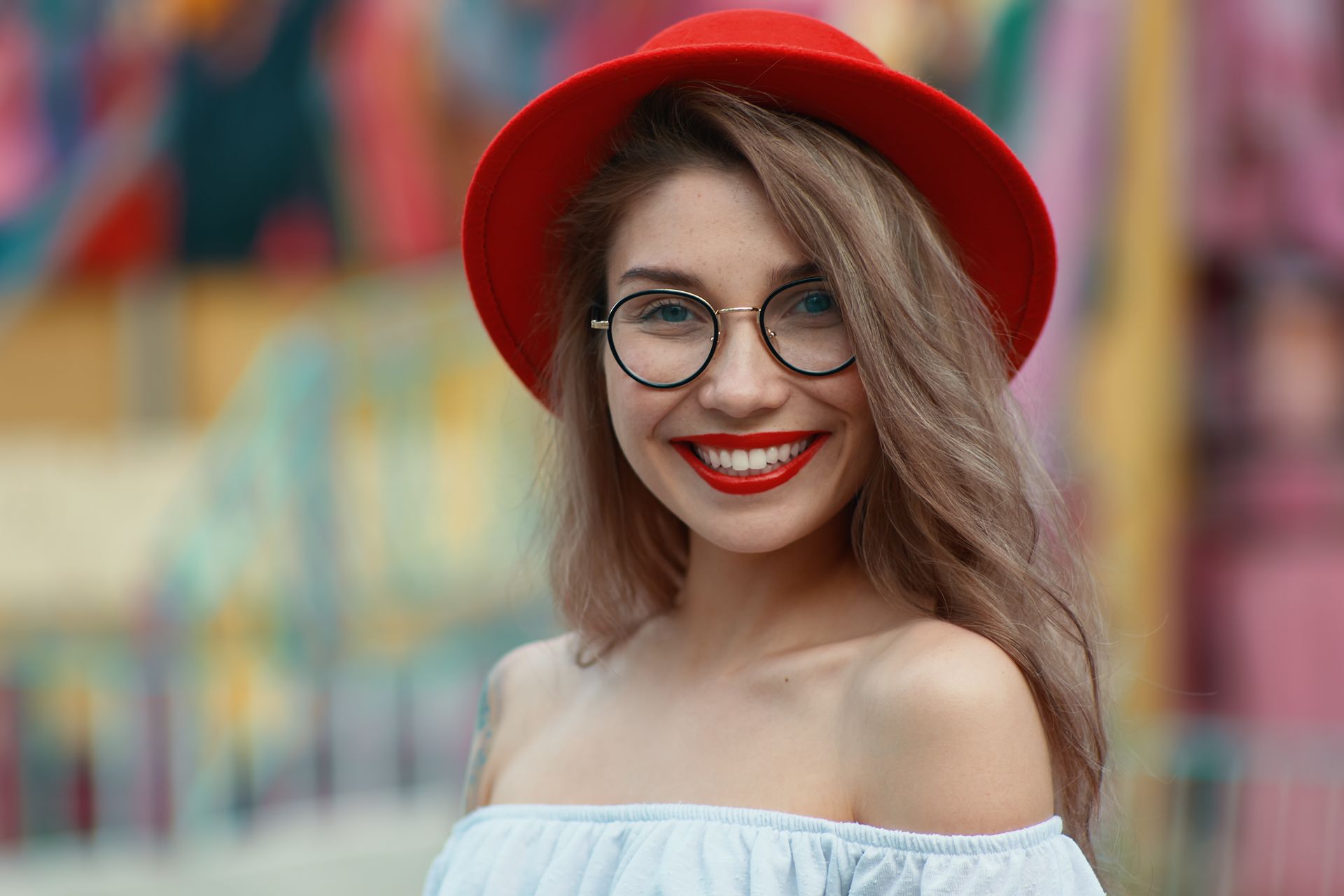 A woman wearing a red hat and glasses is smiling.