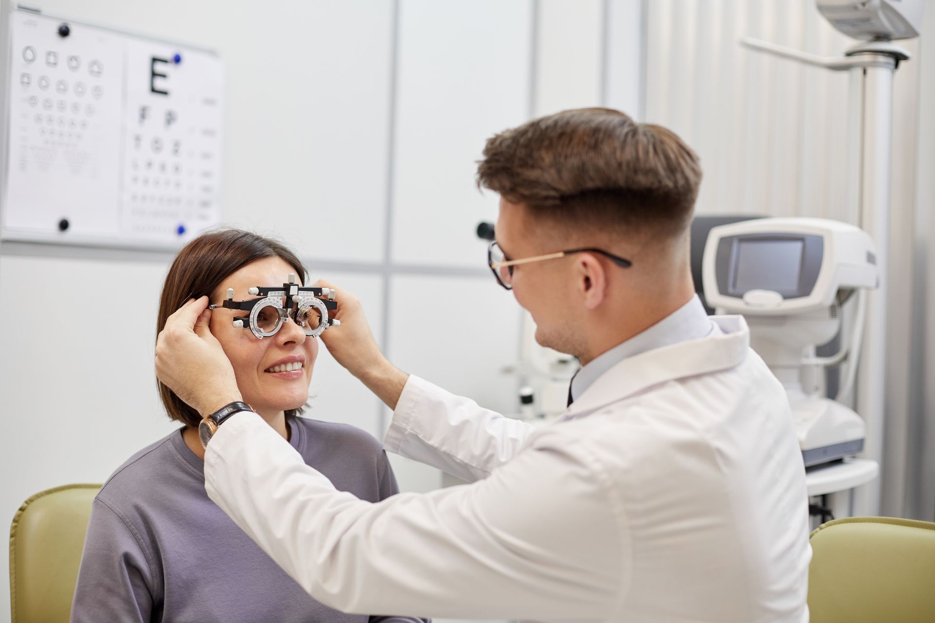 An ophthalmologist is examining a woman 's eye with a pair of glasses.