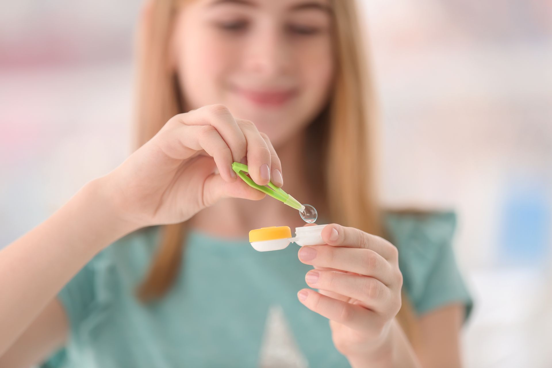 A young girl is putting contact lenses into a contact lens case.