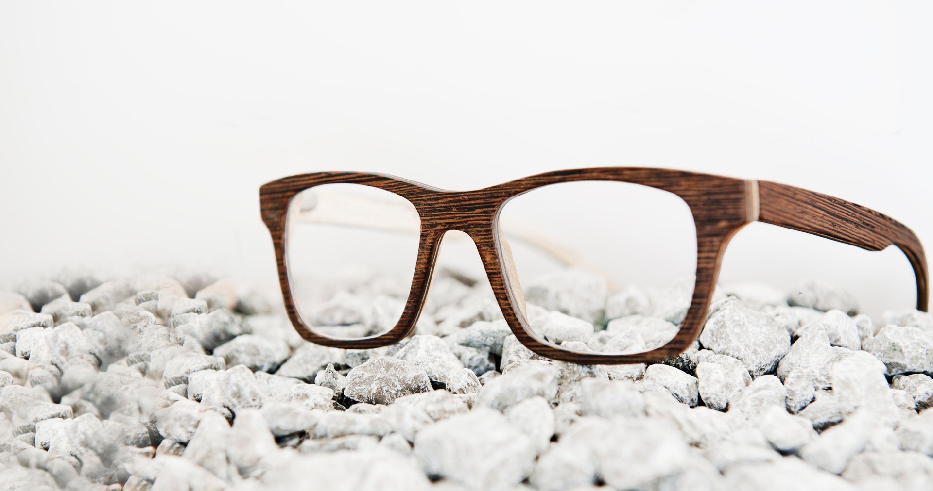 A pair of wooden glasses sitting on top of a pile of rocks.