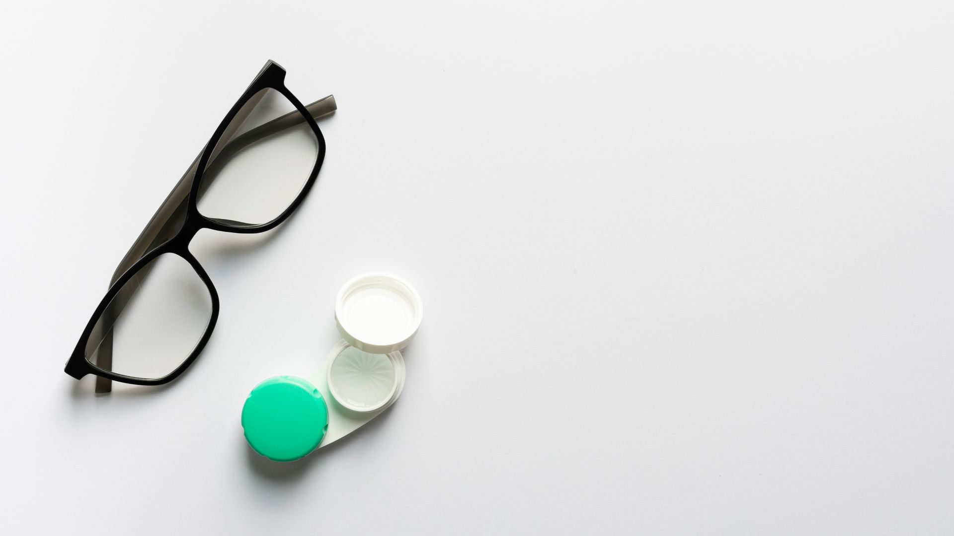 A pair of glasses and a case for contact lenses on a white background.