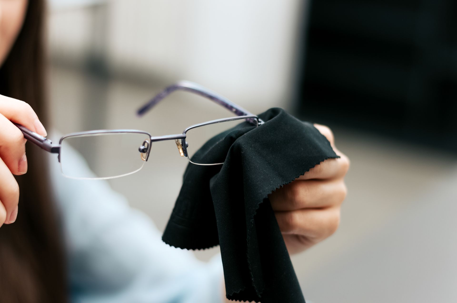 A woman is cleaning her glasses with a cloth.
