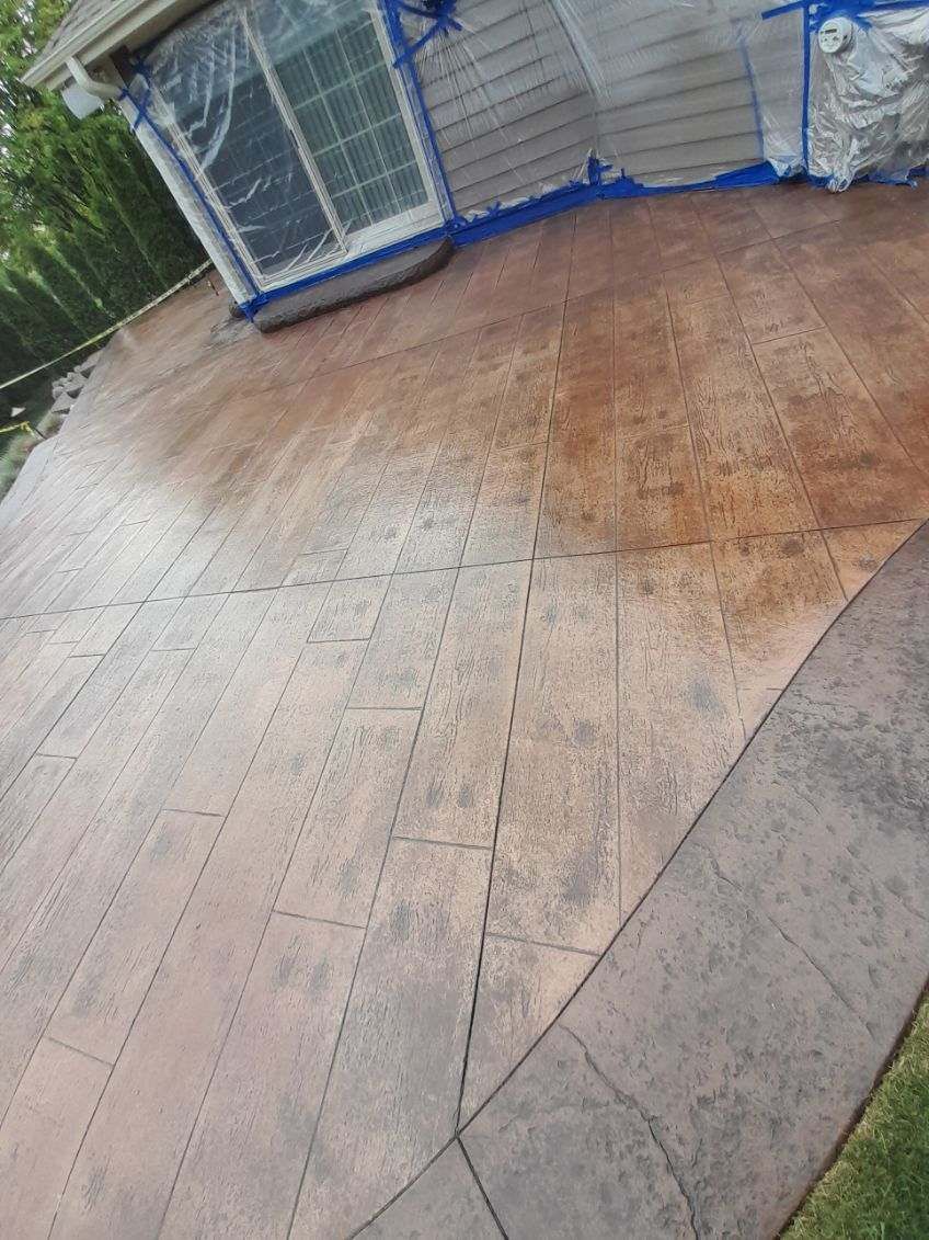 Wet wooden deck beside a fenced outdoor area with blue netting and grass at the edge