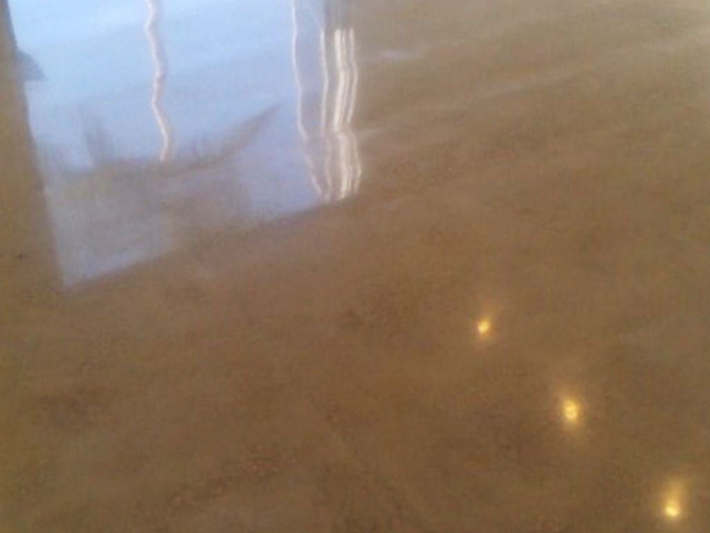 Glossy brown floor reflecting window light and three small ceiling light reflections