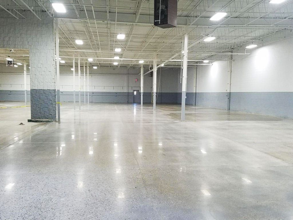Empty warehouse-like room with white columns, blue-gray walls, and polished concrete floor