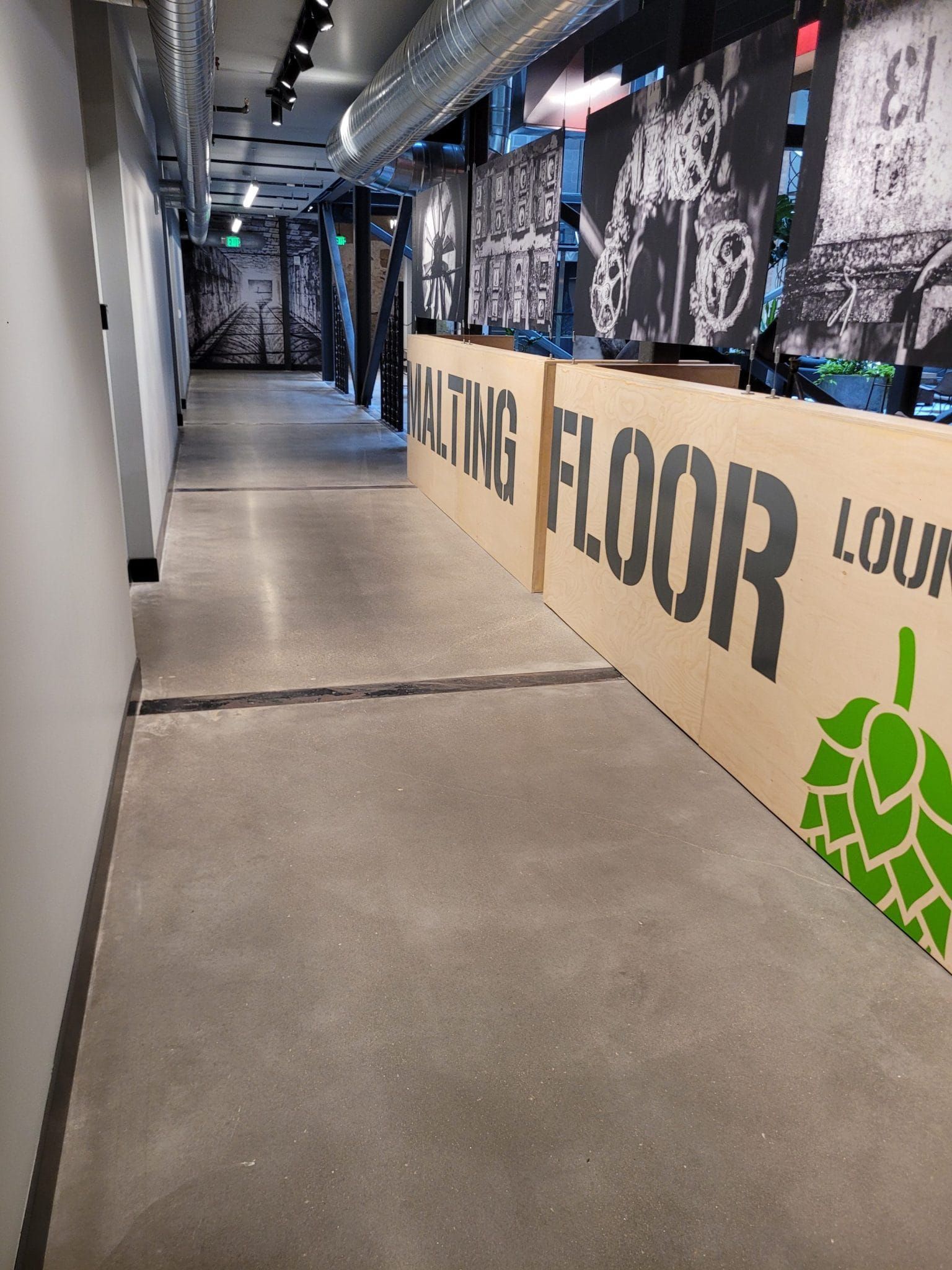 Empty indoor corridor with concrete floor, mural walls, and a large “FIGHTING FLOOR” sign on the right