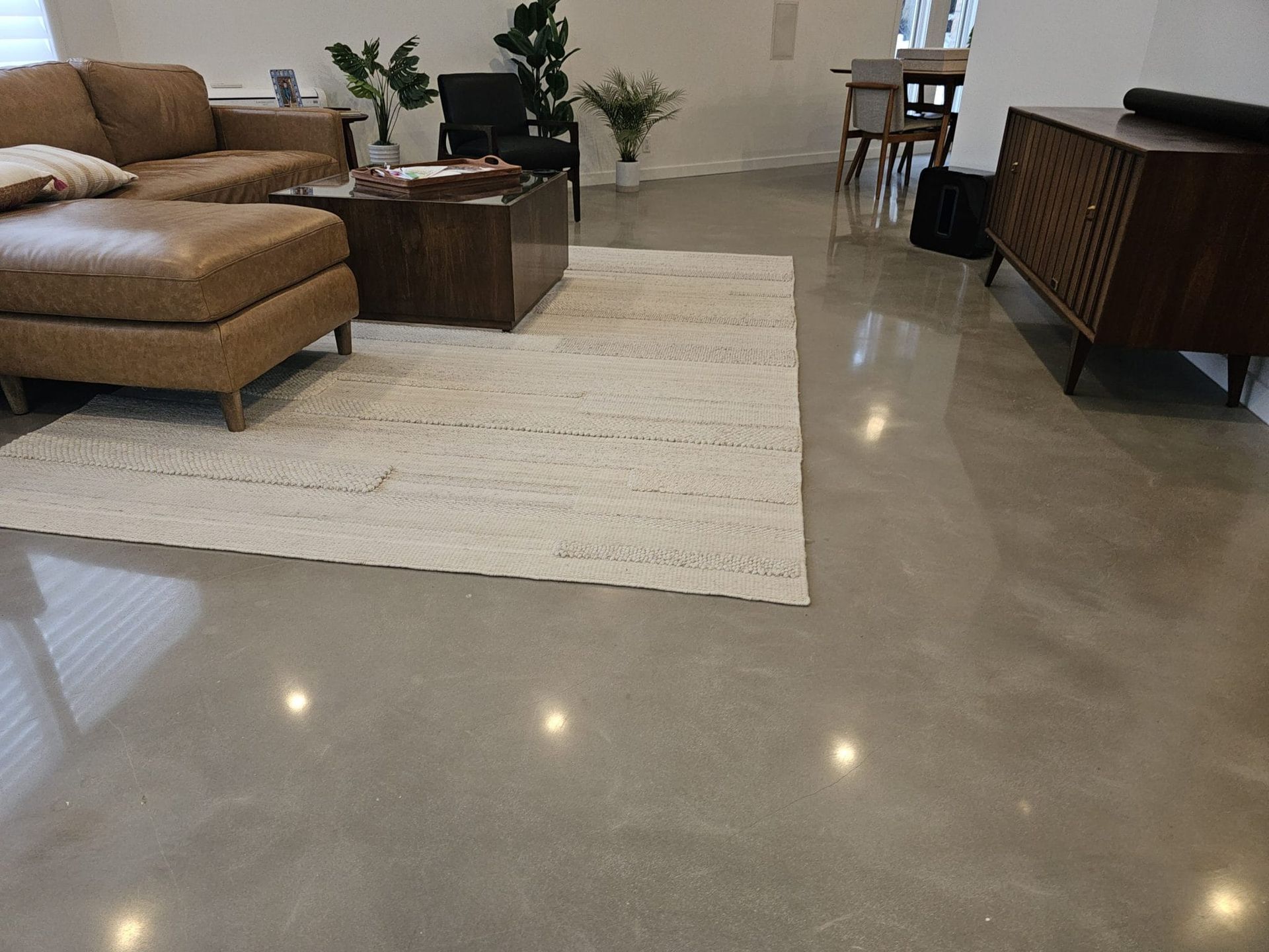 Modern living room with tan sectional, white rug, polished floor, and dark wood furniture