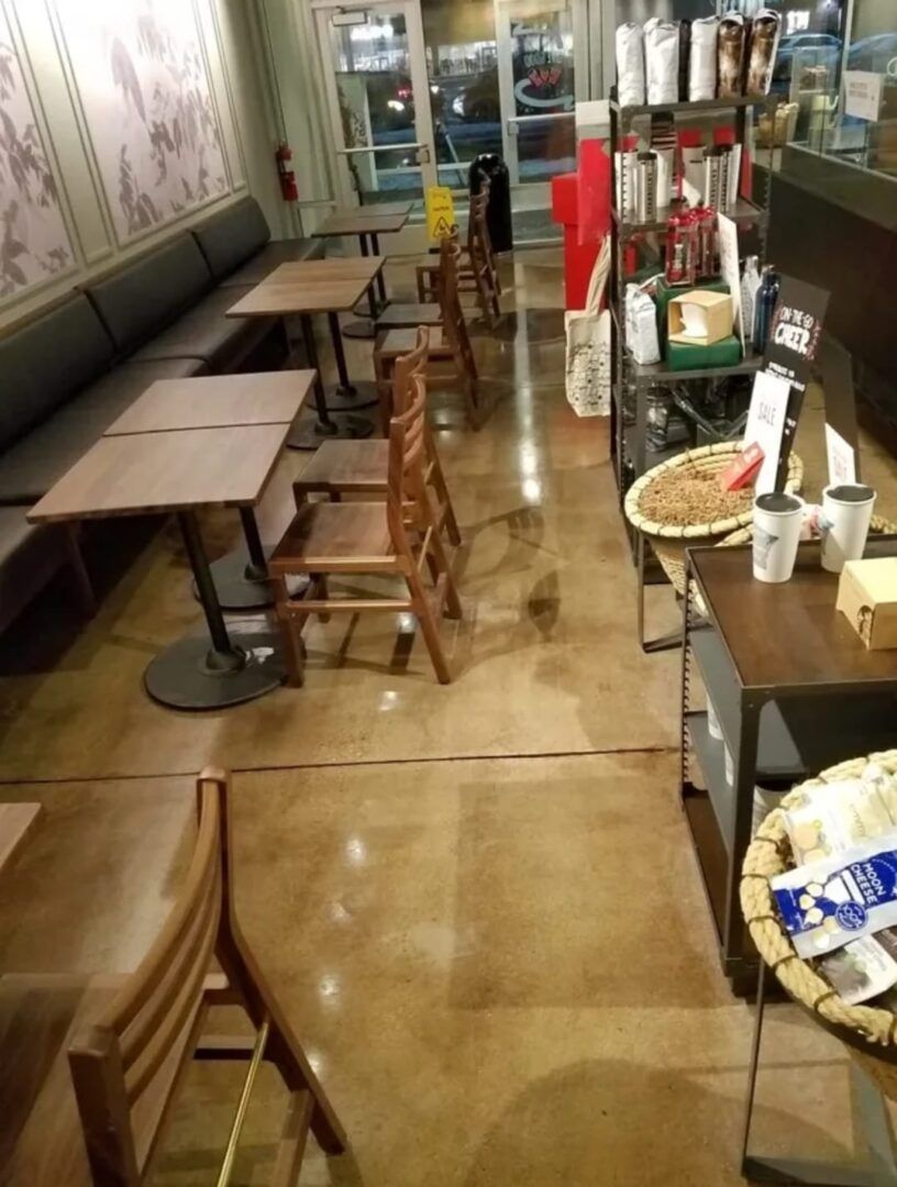 Empty restaurant aisle with wooden tables and chairs, counter on the right, and daylight through the front window.