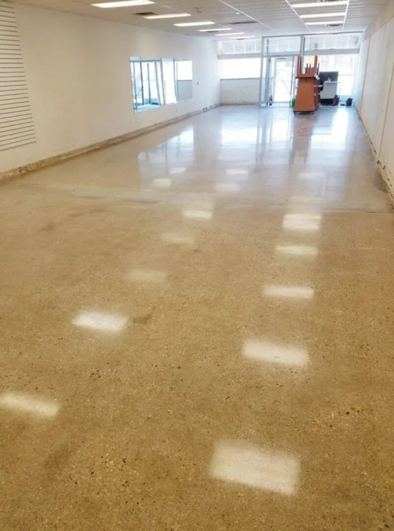 Empty hallway with glossy tile floor, white walls, and windows along one side