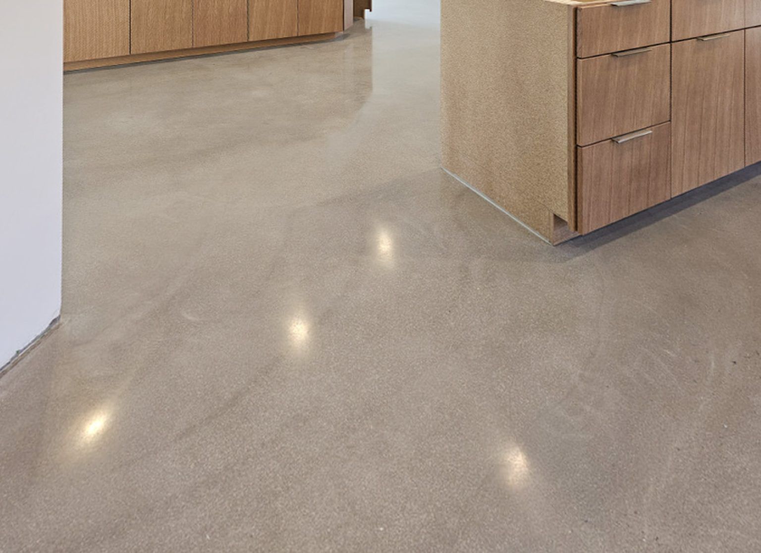 Polished beige kitchen floor with wood cabinets and a doorway visible in the background