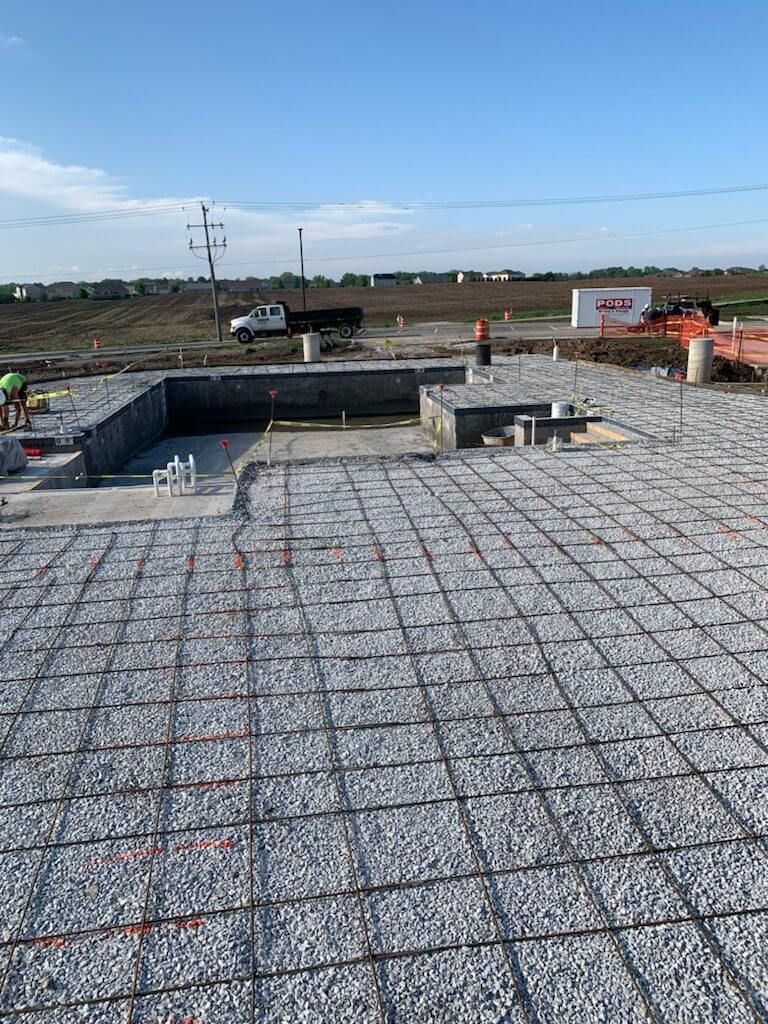 Gravel-covered rooftop construction site with concrete foundation walls and open landscape in the background