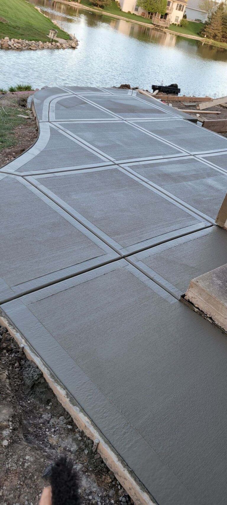 Concrete walkway beside a pond, with diagonal expansion joints and tan edging blocks