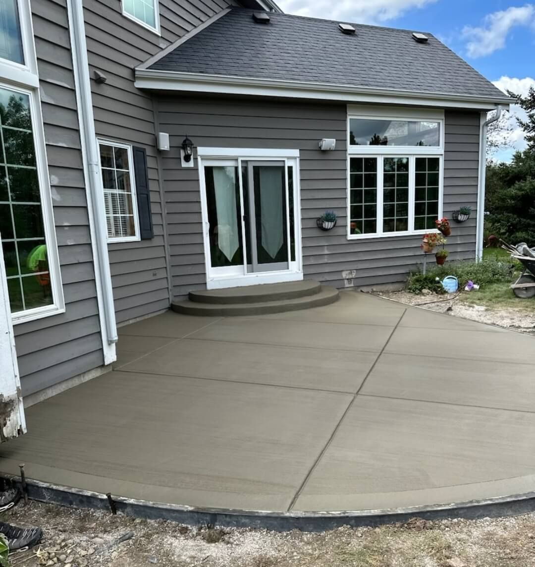 Concrete patio outside a gray house with white French doors and windows
