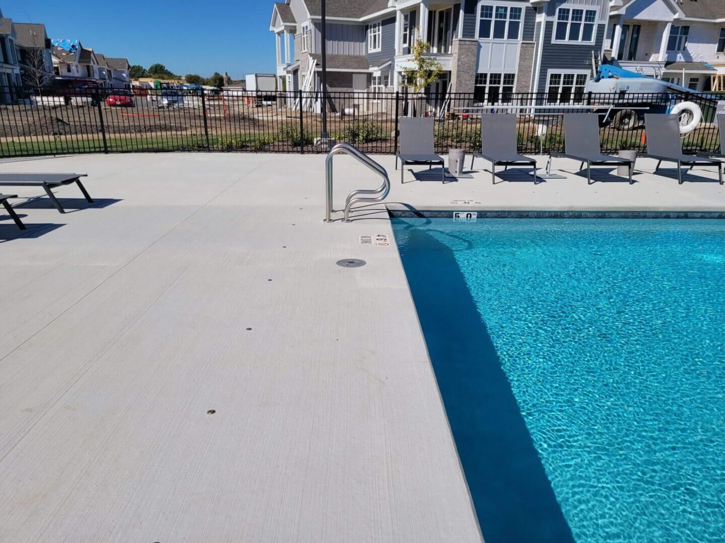 Poolside patio with lounge chairs and waterfront homes in the background