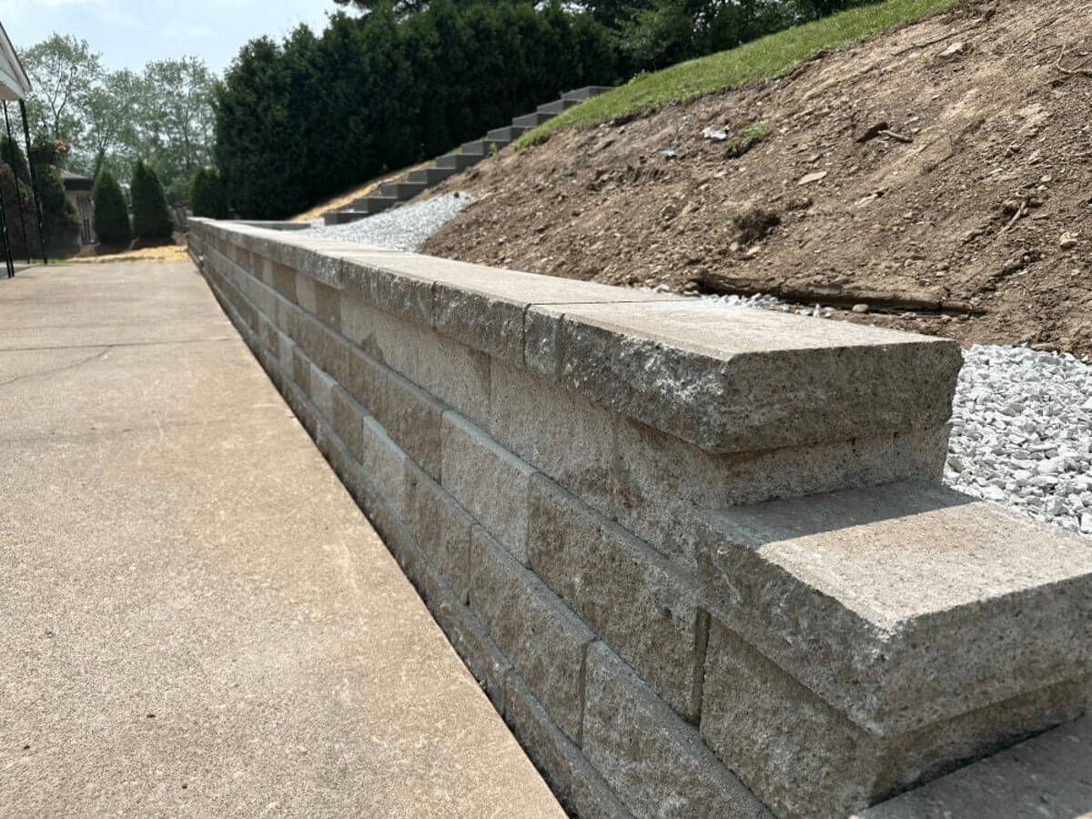 Long concrete retaining wall beside a paved path and grassy slope outdoors