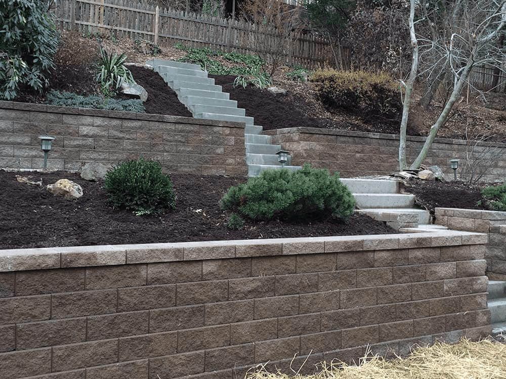 Terraced stone retaining walls and steps in a landscaped backyard garden