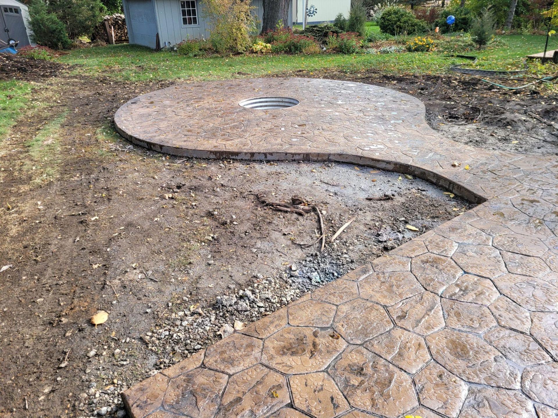 Damaged circular concrete patio with a large crack and sunken section in a yard