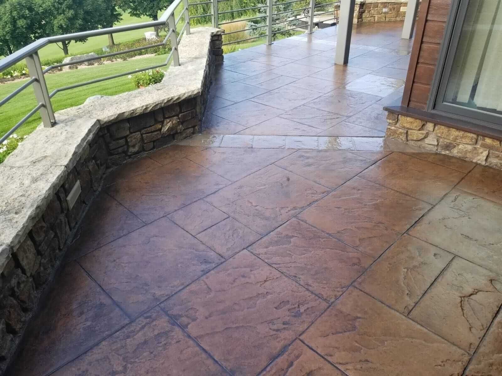 Stone patio with terracotta tiles and a railing overlooking a green landscape