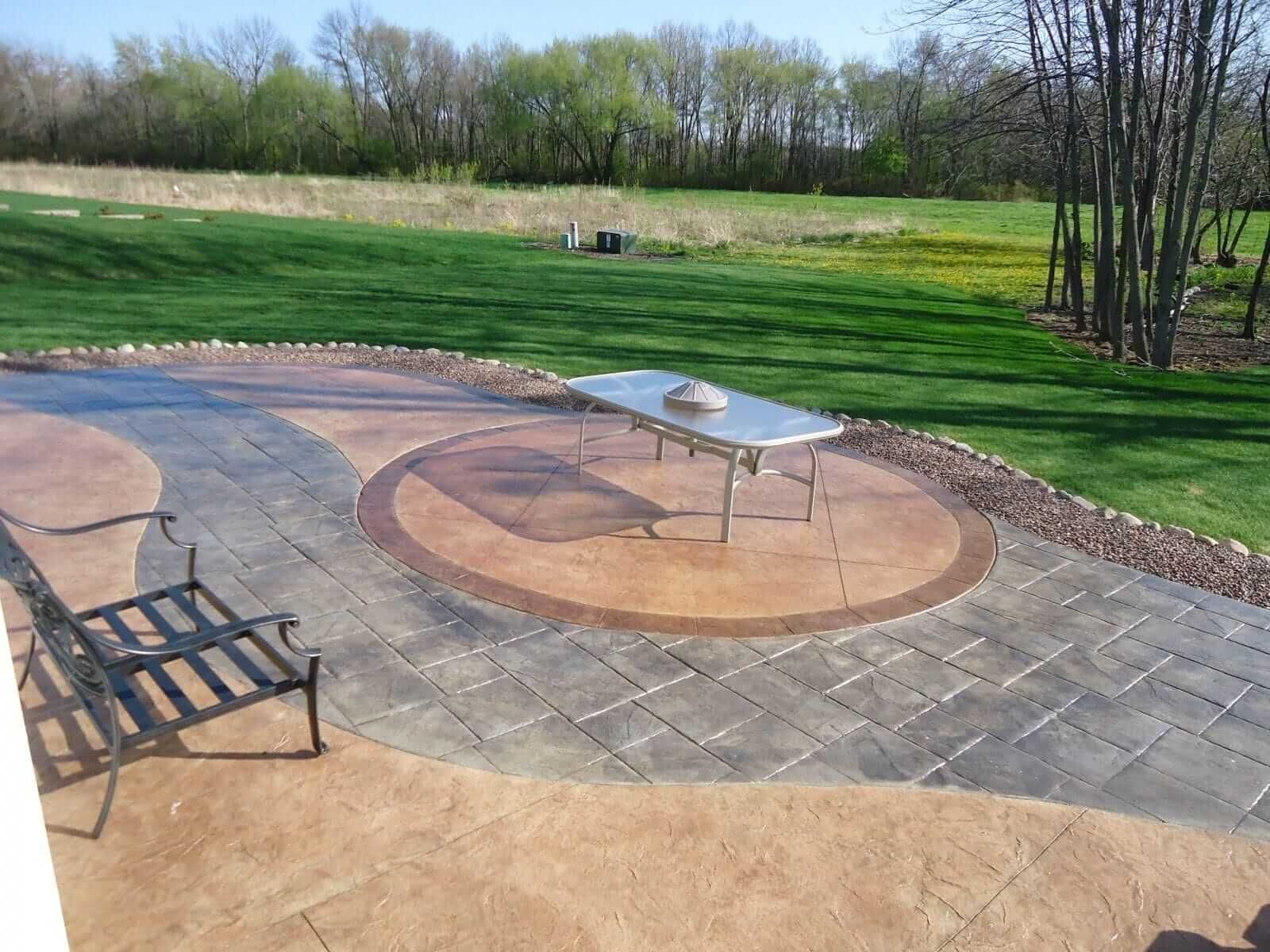 Patio with fire pit, bench, and table overlooking a grassy yard and trees