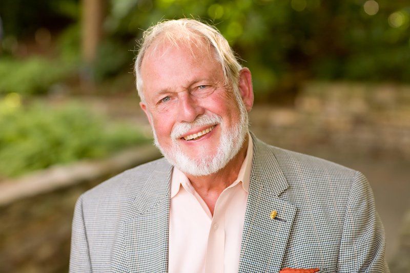 a man with a beard and a suit is smiling for the camera .
