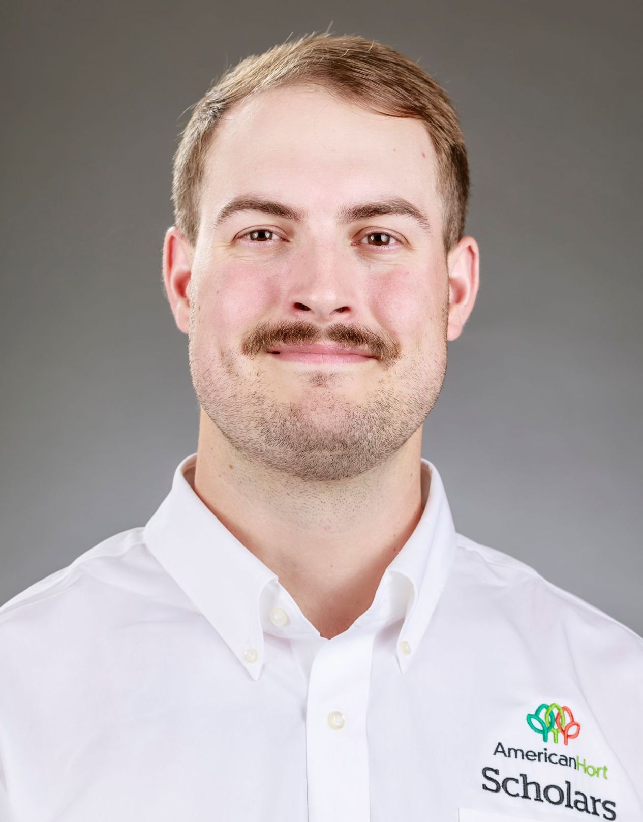 A man with a beard and mustache is wearing a white shirt.