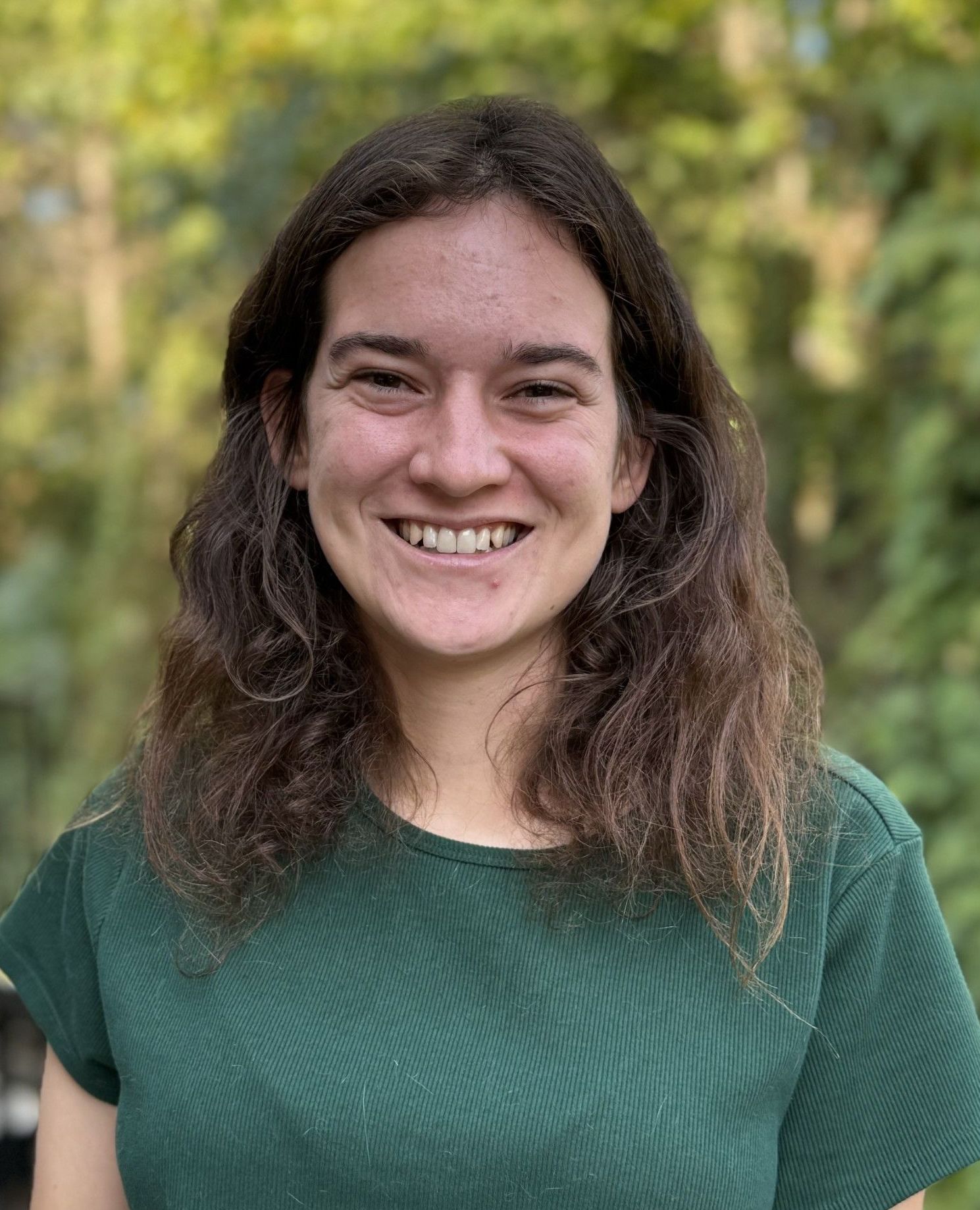 The woman is wearing a green shirt and smiling for the camera.
