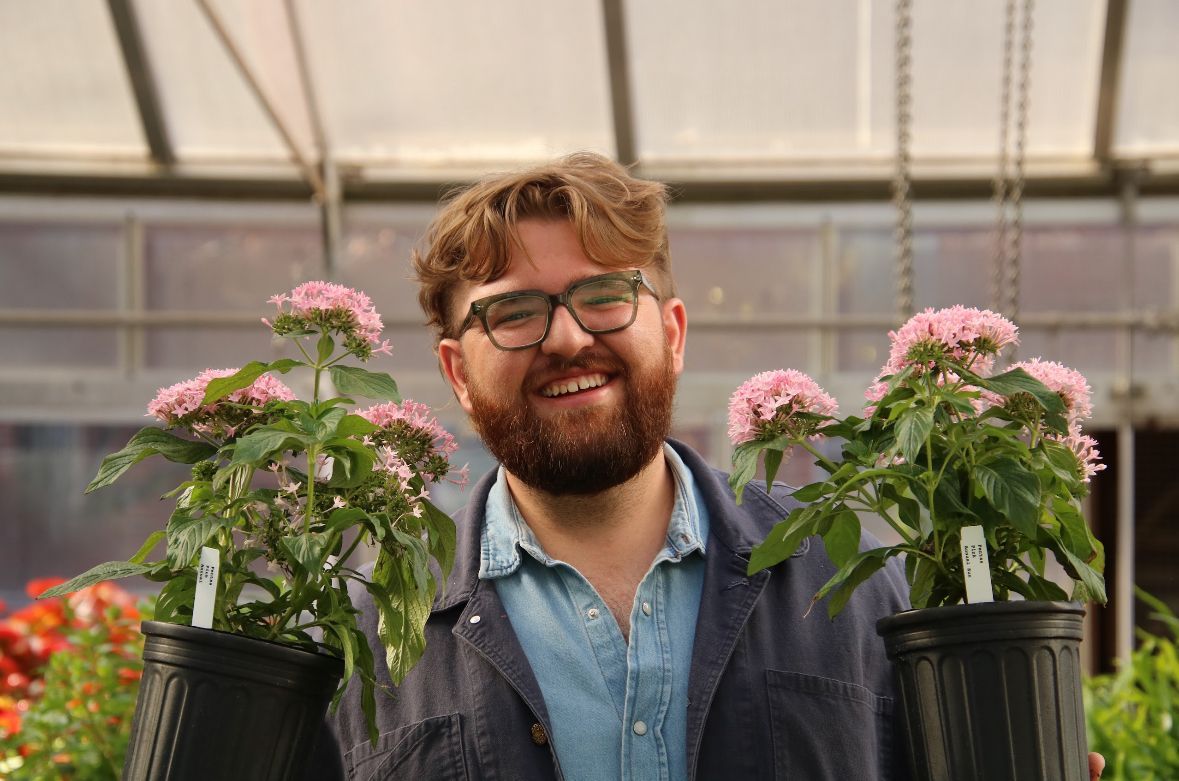 a woman is holding a potted plant in front of a sign that says `` take over '' .