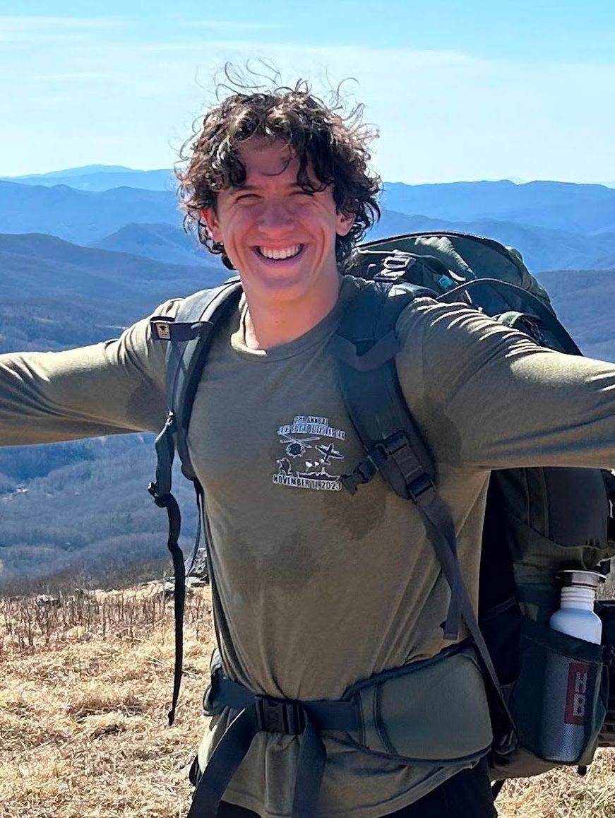 A man with a backpack is standing on top of a mountain.