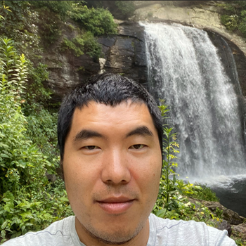 a man is taking a selfie in front of a waterfall .