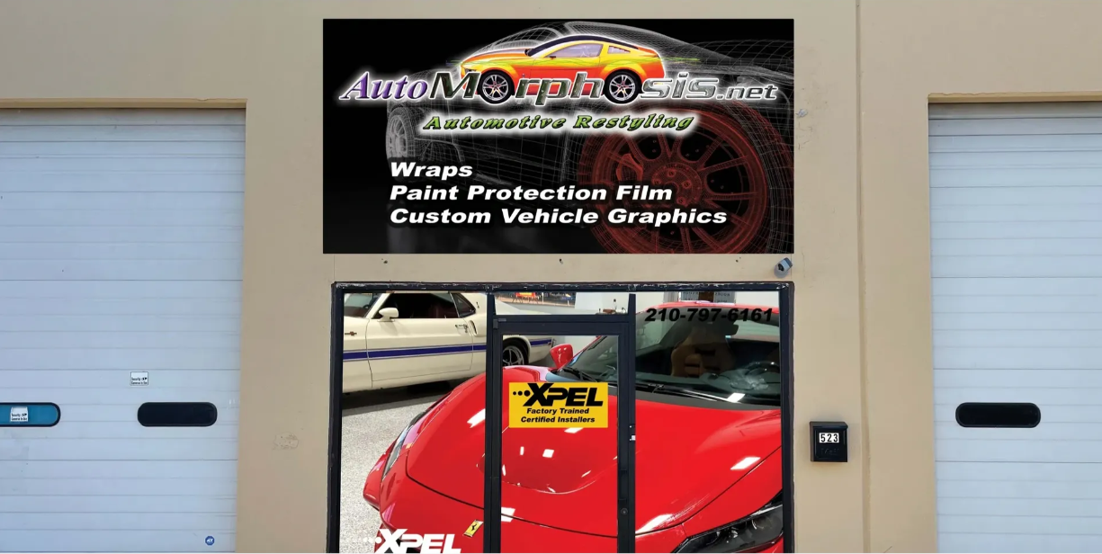 A red car is parked in front of a store that sells wraps paint protection film and custom vehicle graphics