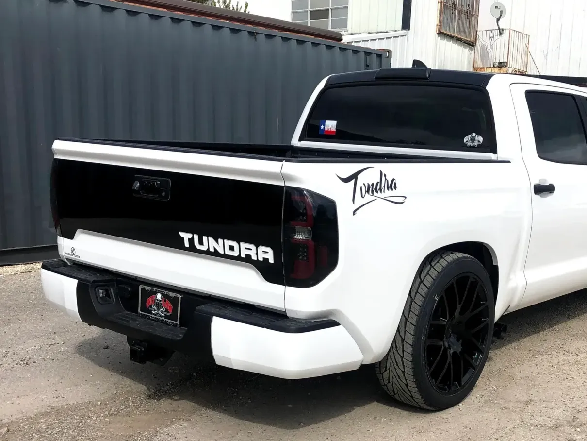 A white toyota tundra truck is parked in front of a building.