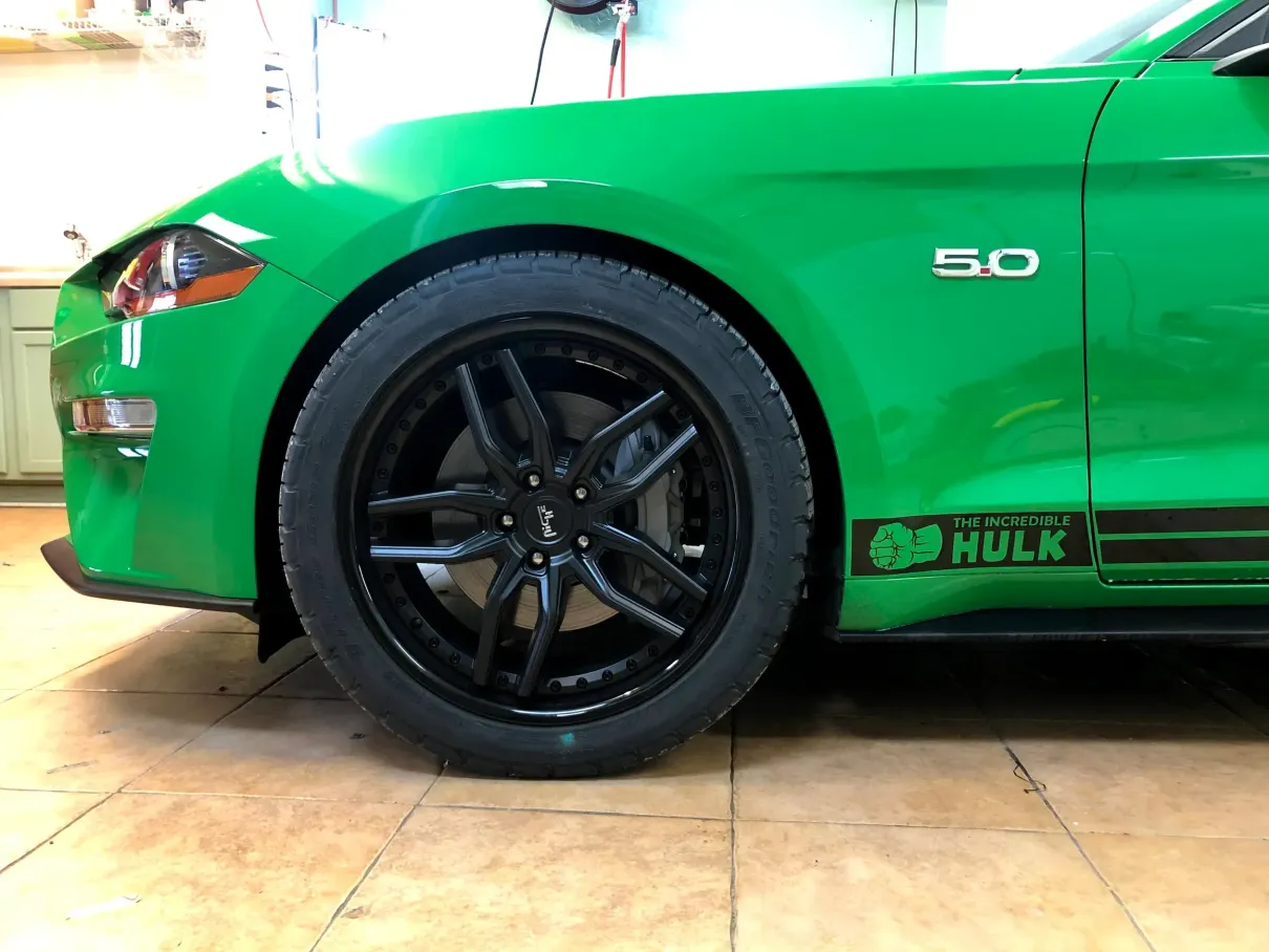 A green mustang with a hulk sticker on the side