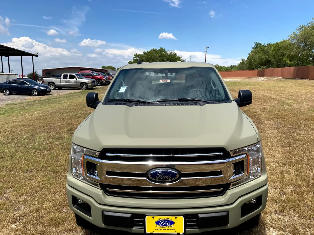 A green ford truck is parked in a grassy field.