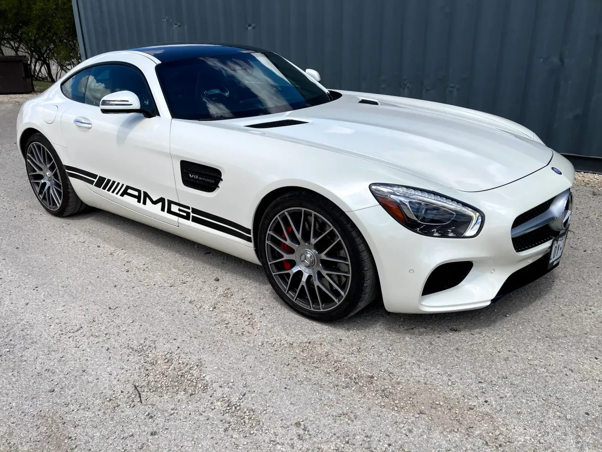 A white mercedes amg gt is parked in front of a building.