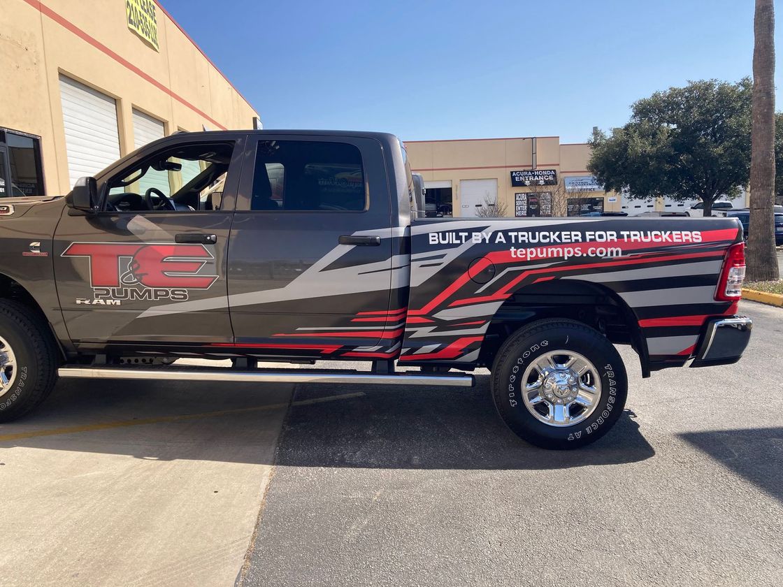 A truck with a t on the side is parked in front of a building.