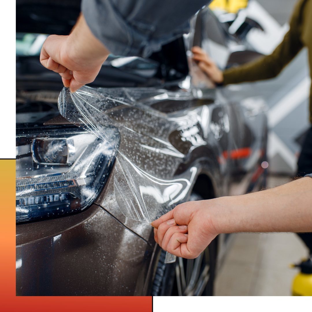 A person is applying a clear plastic covering to a car 's headlight.