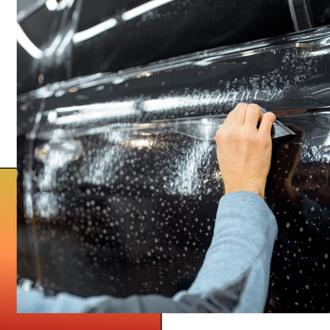 A person is applying a clear film to a car door