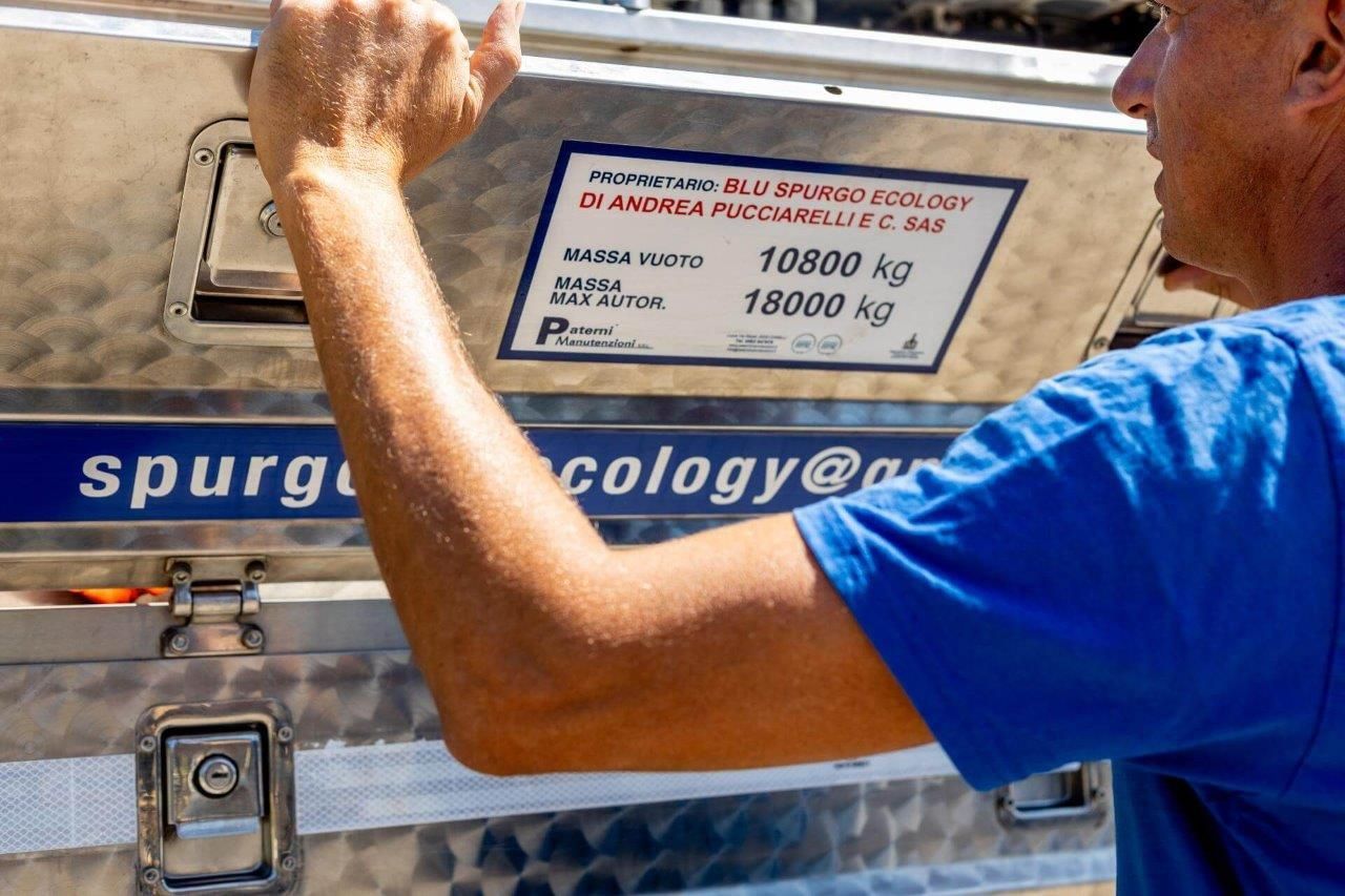 Uomo che apre una scatola di metallo con un'etichetta che indica i limiti di peso, all'aperto.