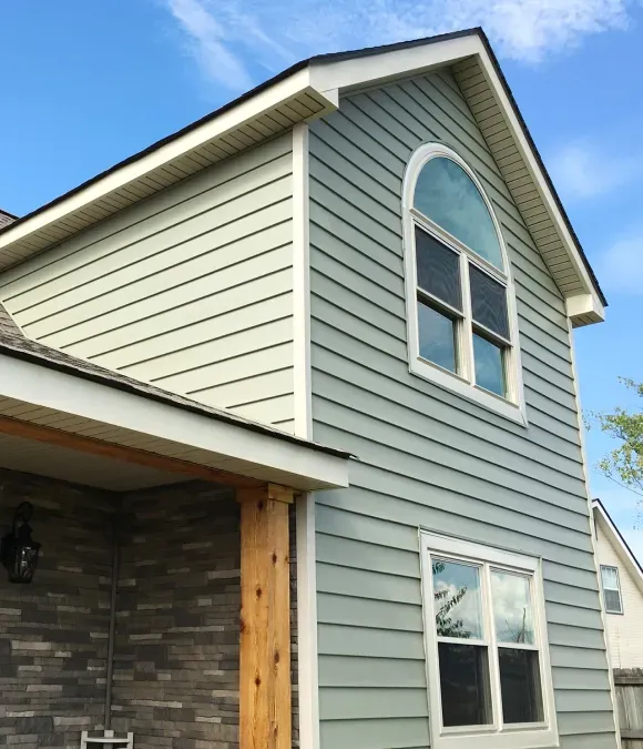 Two-story house with light blue siding, white trim, and a large arched window.