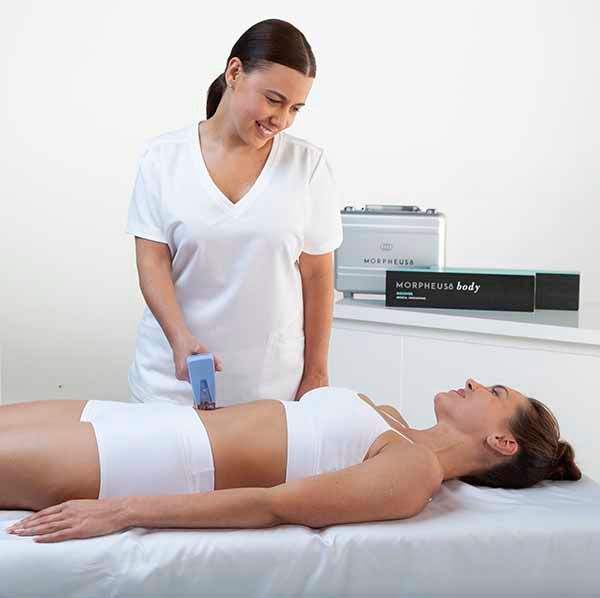 A woman is laying on a bed getting a massage from a nurse.