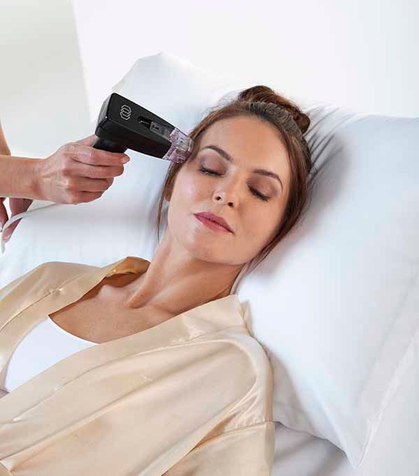 A woman is laying in a bed getting a facial treatment.