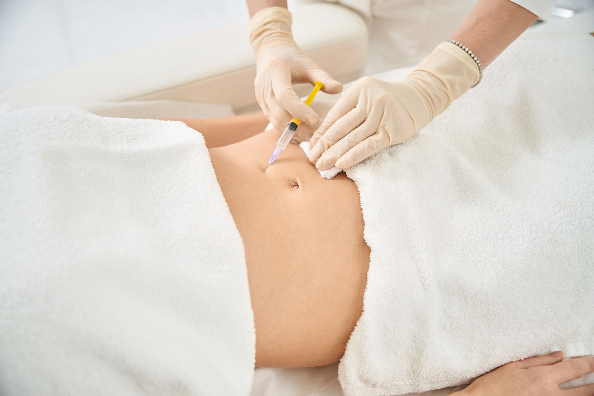 A woman is getting an injection in her stomach.