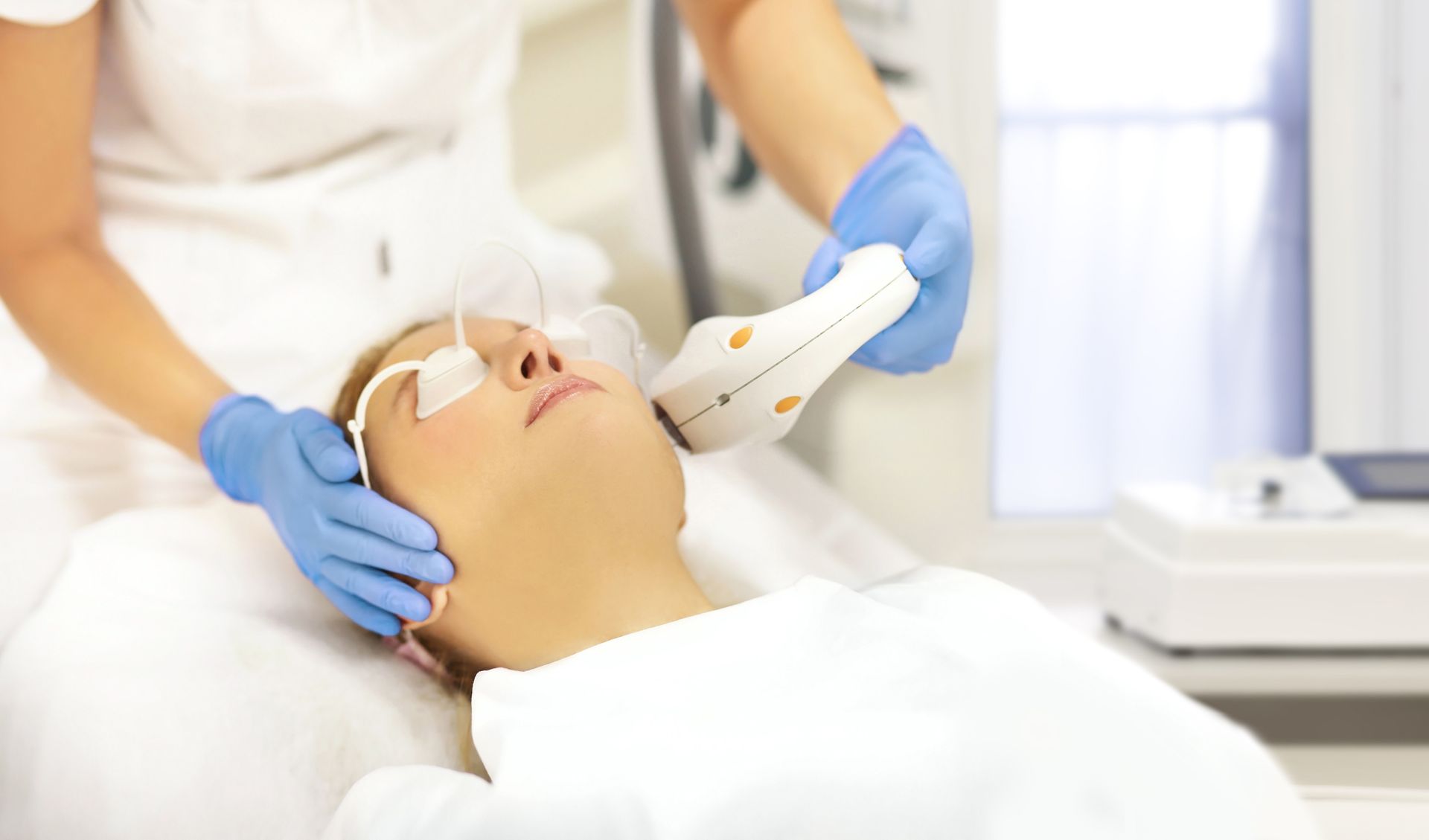 A woman is getting a laser treatment on her face.