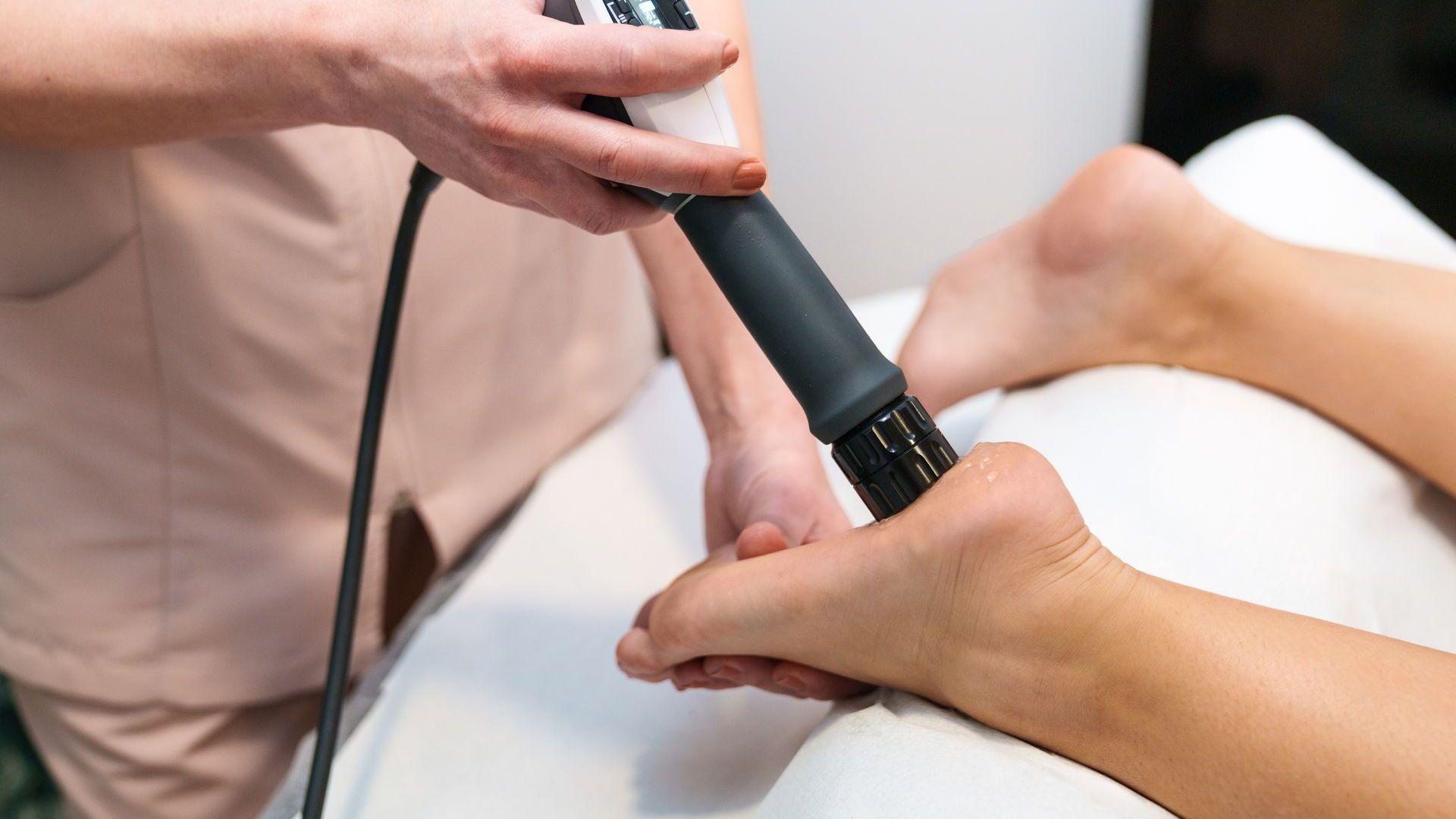 A woman is using a machine on a patient 's foot.