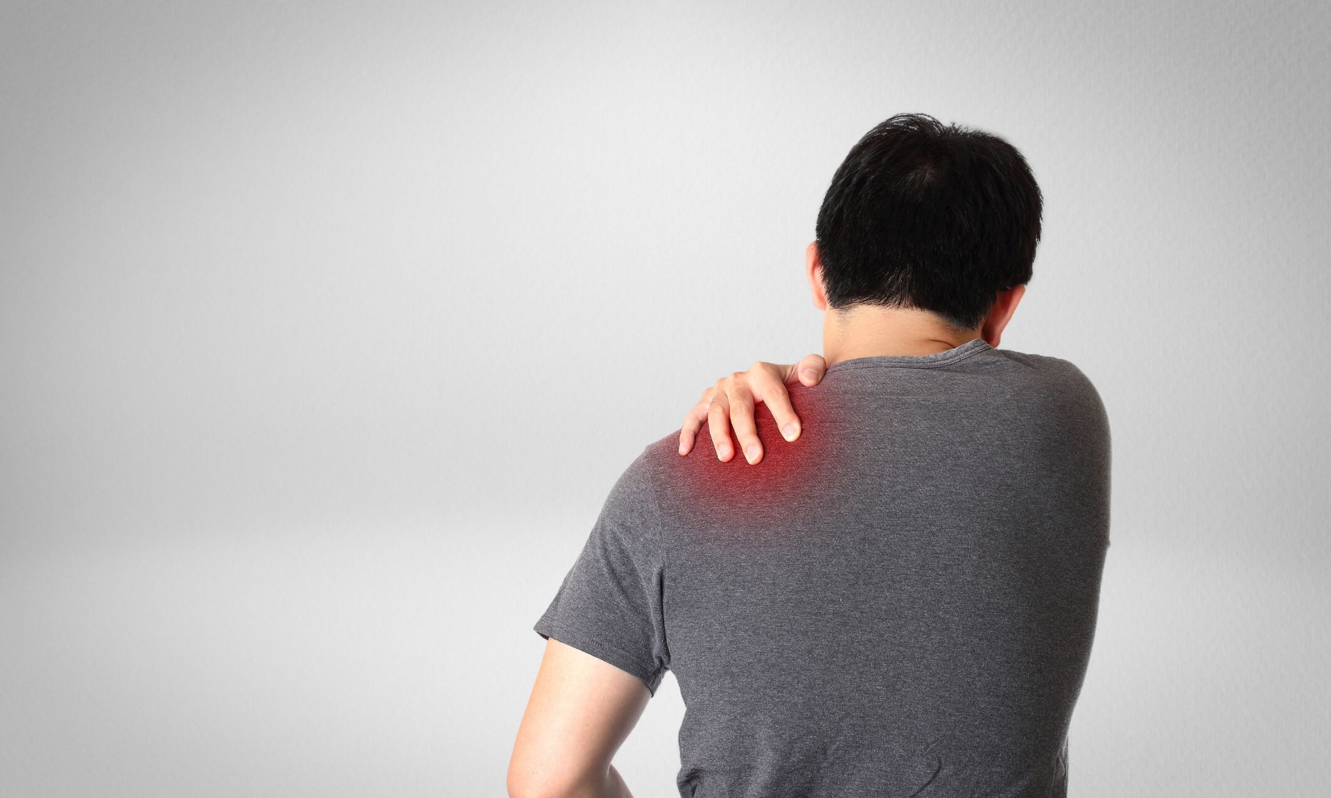 A man is holding his shoulder in pain.