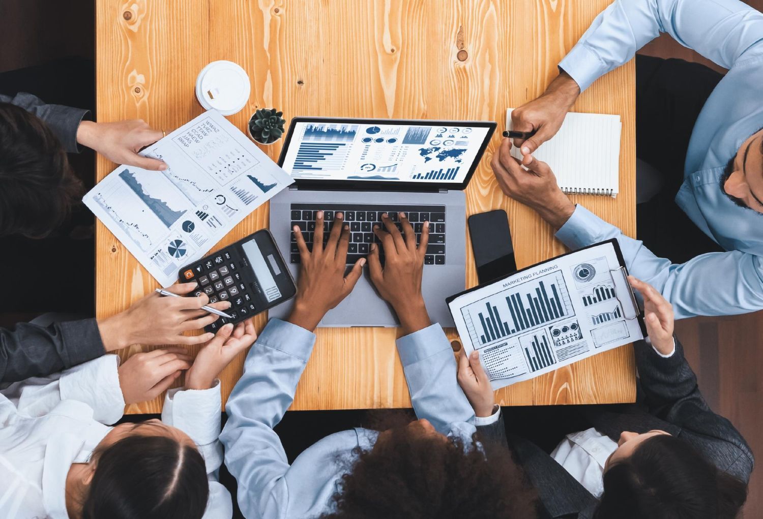 A man and a woman are sitting at a table looking at a laptop.