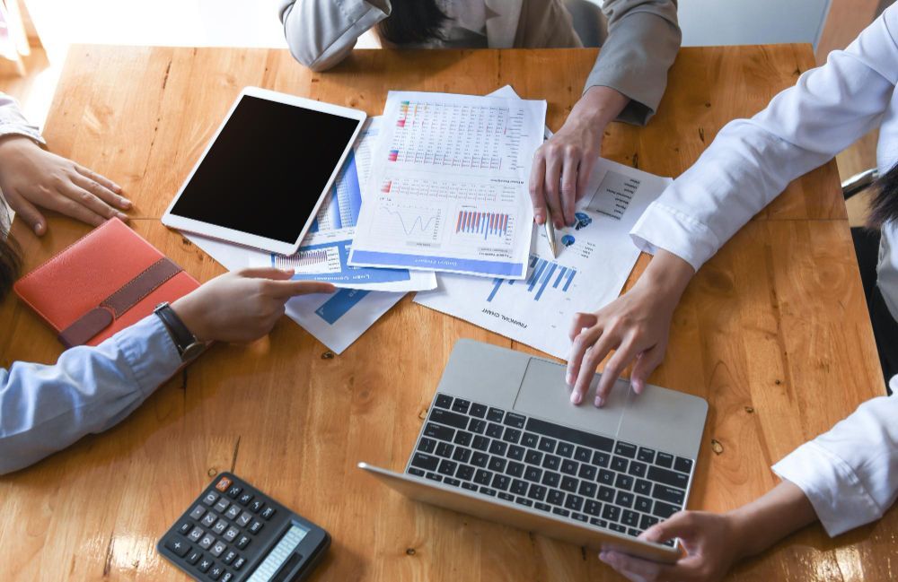A man and a woman are sitting at a table looking at a laptop.