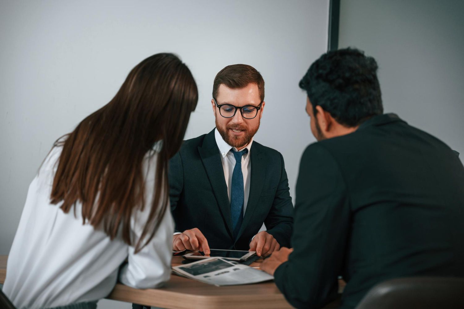 A man and a woman are sitting at a table looking at a laptop.