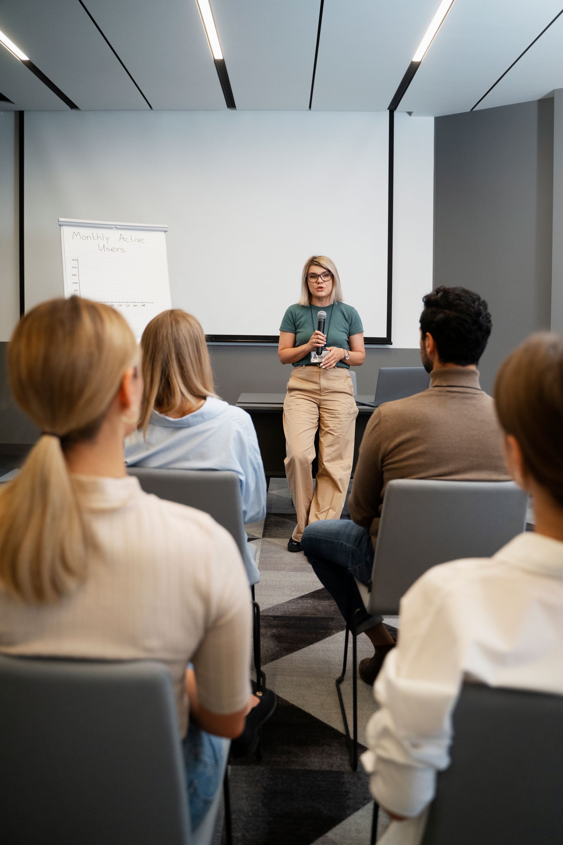 A woman is giving a presentation to a group of people in a conference room.