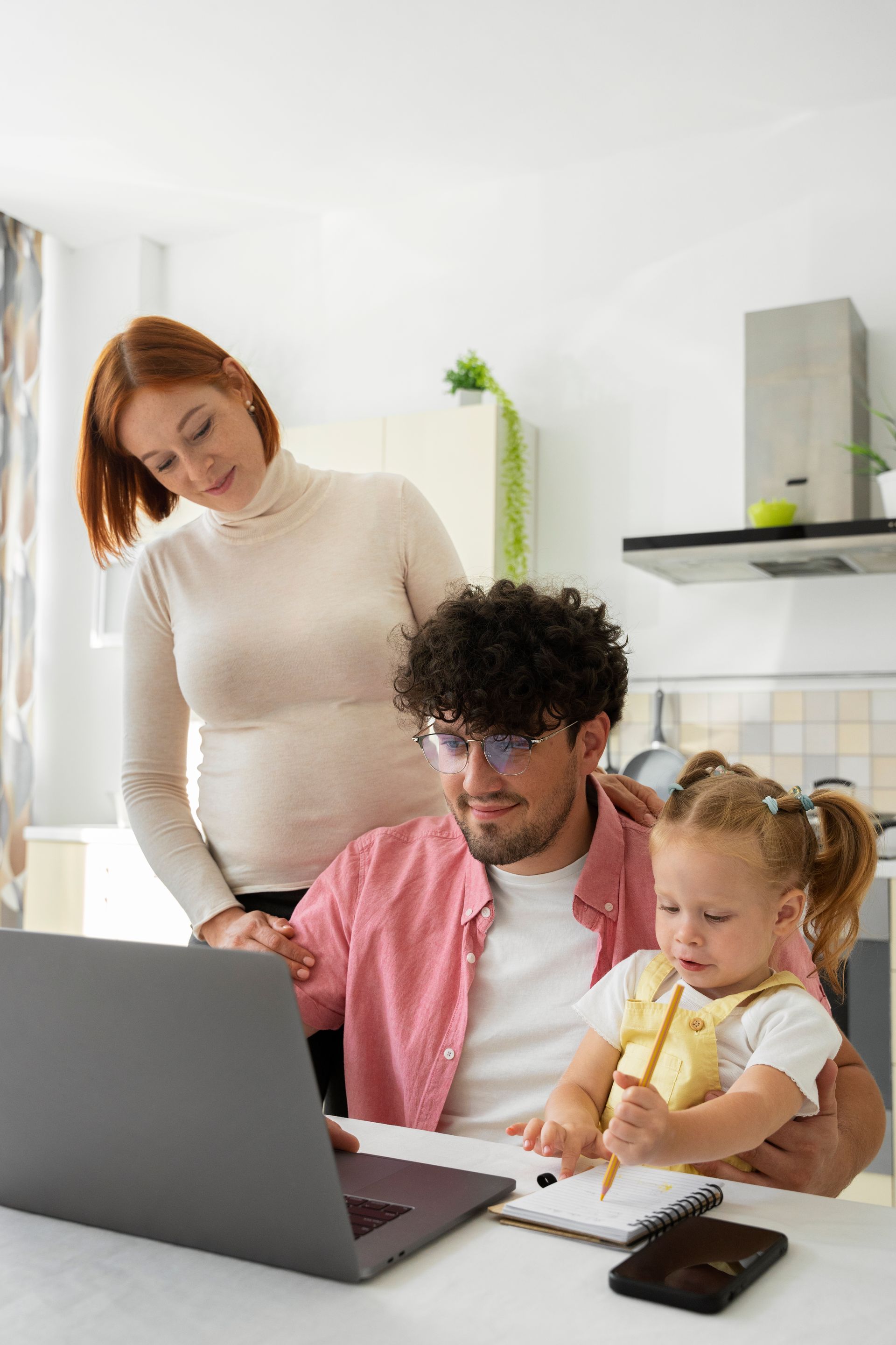A man is sitting at a table with a laptop and a little girl.